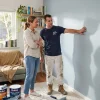 A homeowner and painter review a freshly finished living-room wall during a residential painting project.