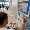 A painter carefully cuts in around a reception directory, refining the wall finish in a commercial lobby.