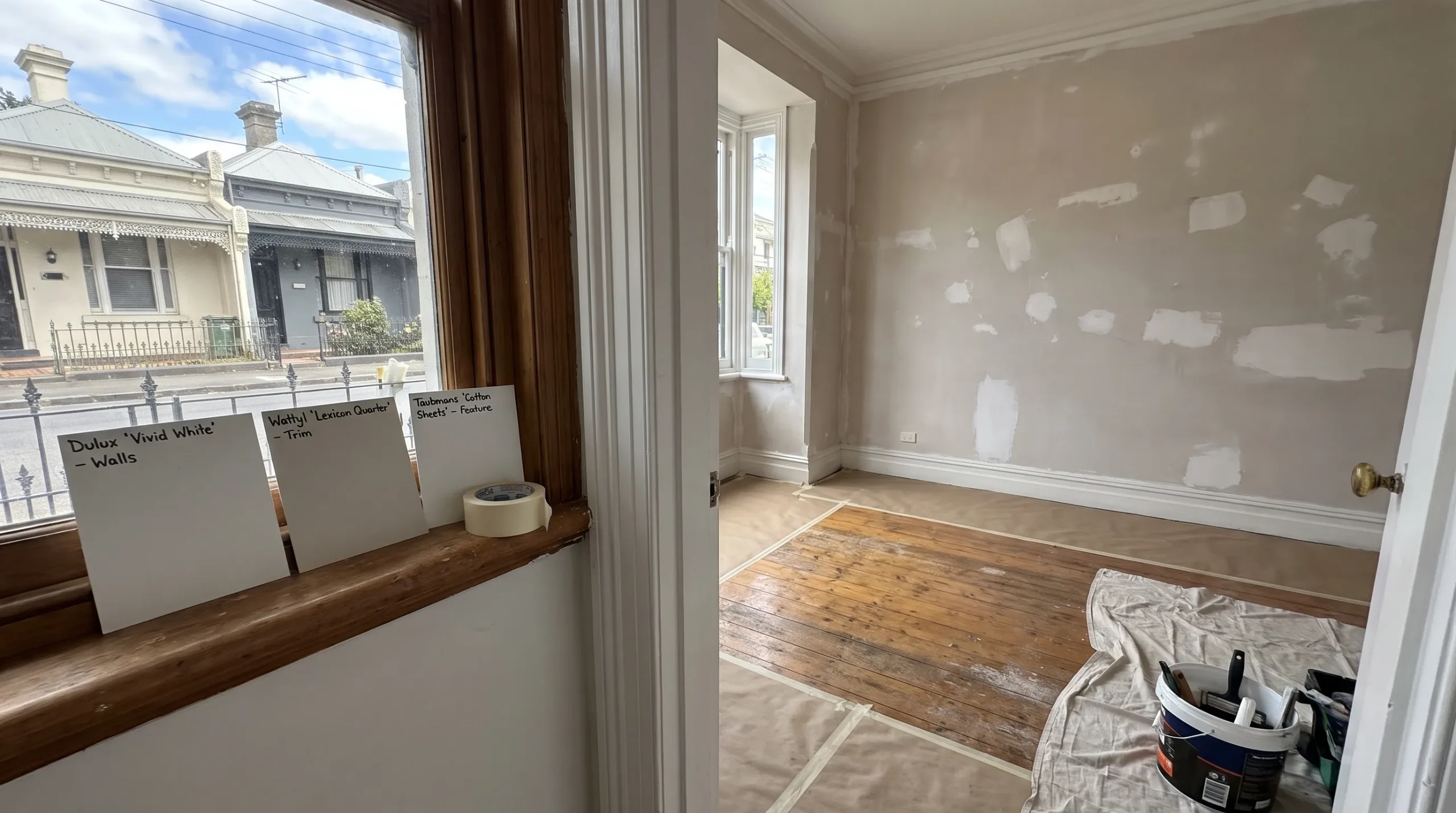 Protected timber flooring and repaired walls are ready for residential painters Melbourne property managers have booked, with labelled samples by the doorway.